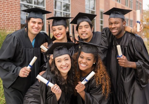 Group of students standing in cap and gowns with their diplomas in hand.
